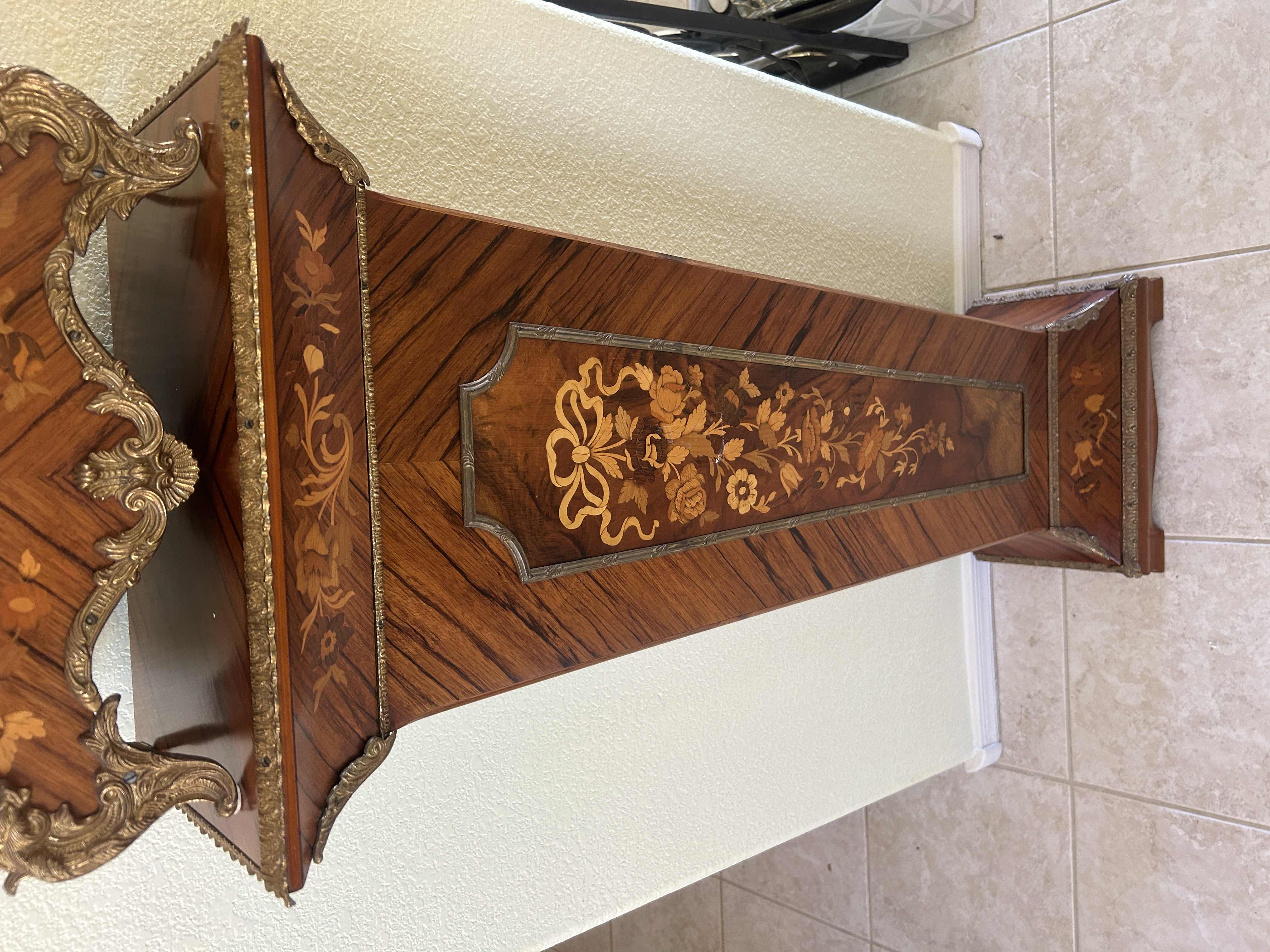 Photo 1 of TIFFANY MADE IN ITALY - FRENCH STYLE VERSAILLES CLOCK FEATURES AN ORNATE GILDED METAL CASE WITH ELABORATE SCROLLWORK, FLORAL MOTIFS, AND A DECORATIVE FINIAL. MATCHING PEDESTAL 14 1/2“ x 6 1/4“ x H31“ PEDESTAL16 1/2” x 9 1/2” x H 44 1/2” TOTAL HEIGHT, INCL
