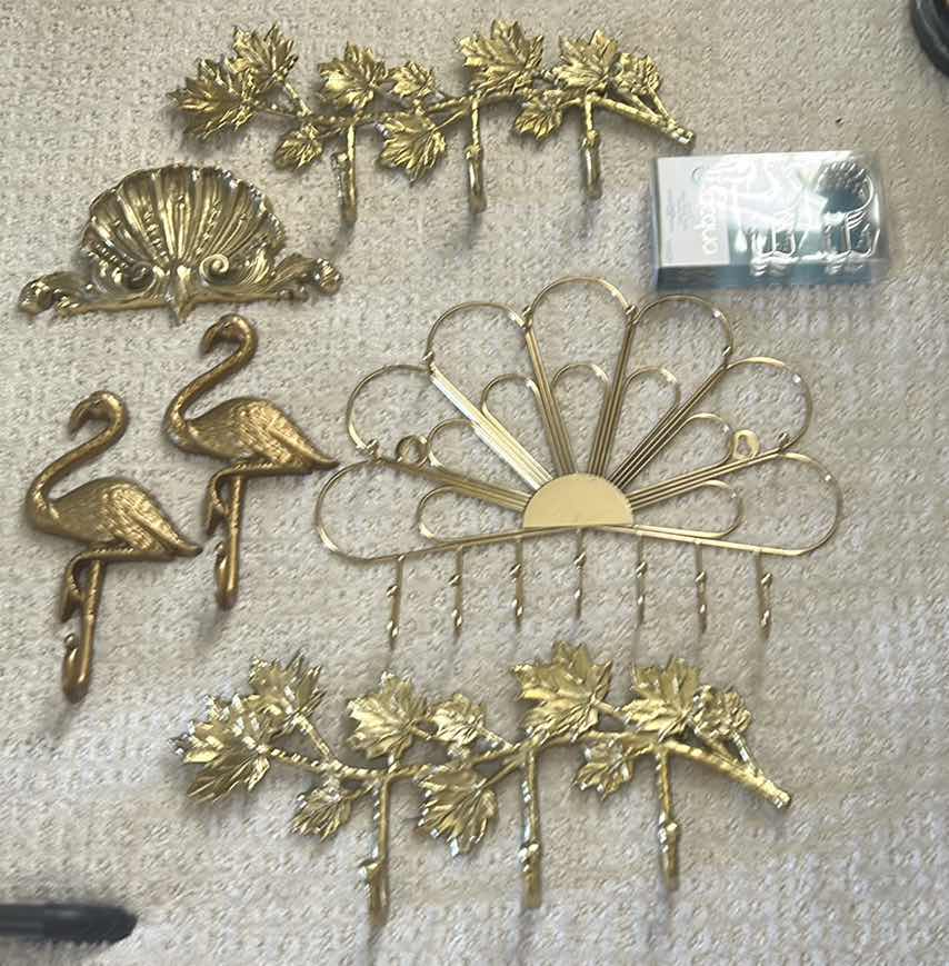Photo 1 of GOLD-COLORED METAL WALL RACKS FEATURING HOOKS FOR ORGANIZING ITEMS.