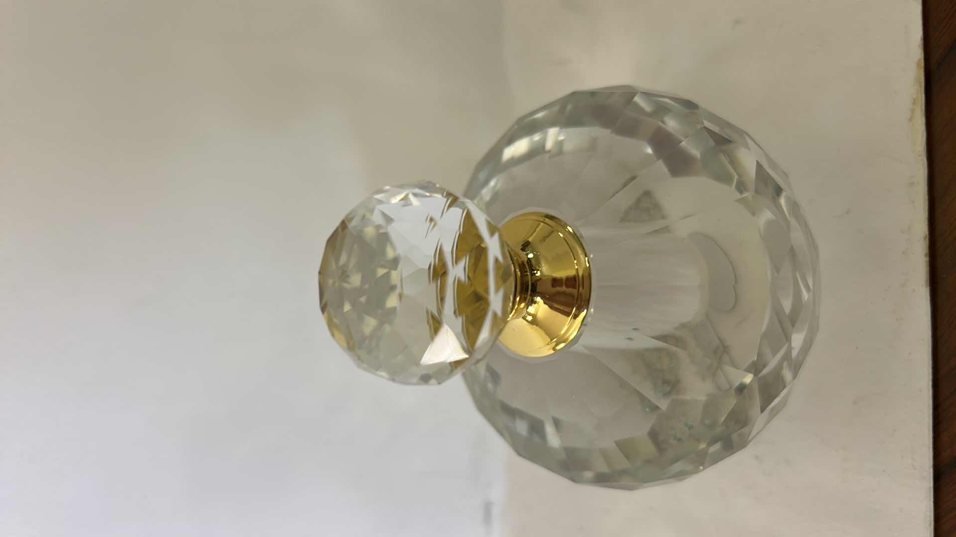 Photo 1 of FACETED CRYSTAL PERFUME BOTTLE FEATURES A DECORATIVE GOLD CAP AND A DISTINCT DIAMOND-SHAPED STOPPER.