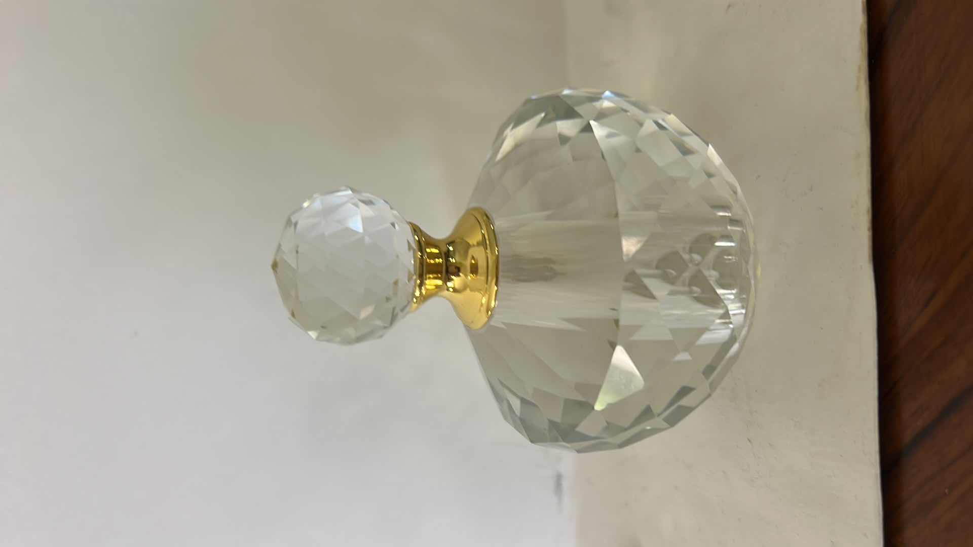Photo 1 of FACETED CRYSTAL PERFUME BOTTLE FEATURES A DECORATIVE GOLD CAP AND A DISTINCT DIAMOND-SHAPED STOPPER.