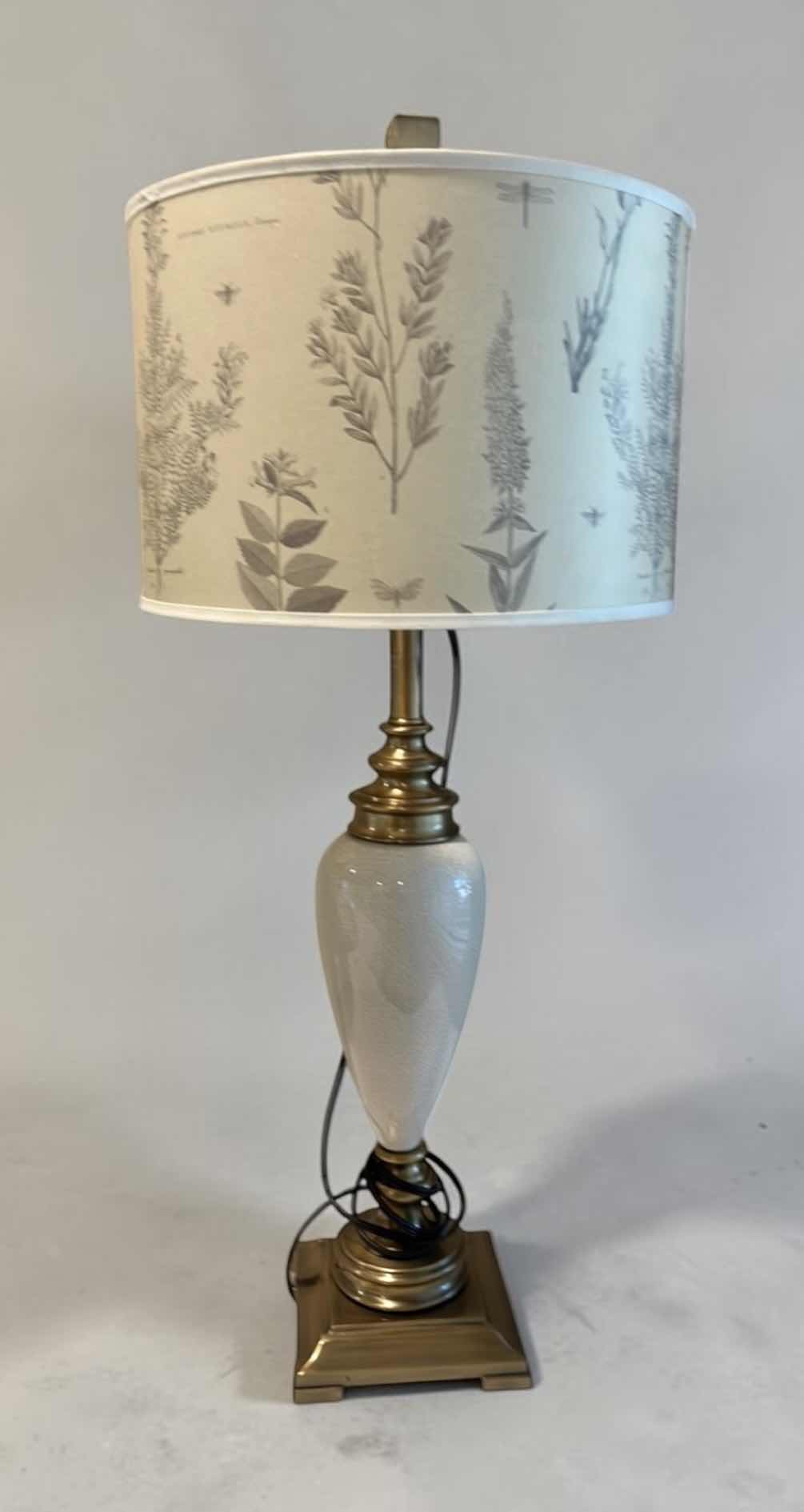 Photo 1 of TABLE LAMP FEATURES A WHITE CERAMIC VASE BODY AND A BOTANICAL PATTERNED SHADE. H34”