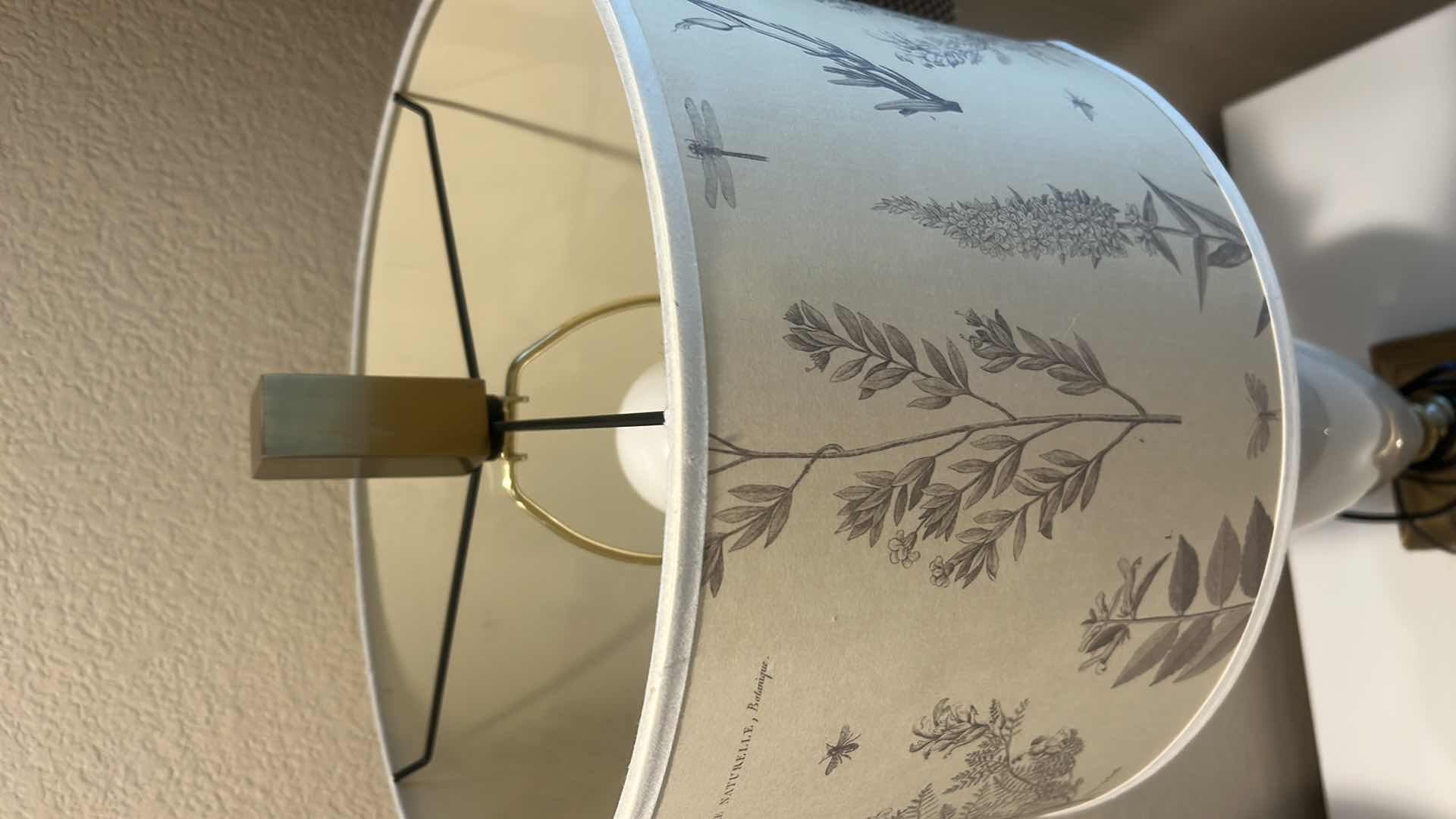 Photo 1 of TABLE LAMP FEATURES A WHITE CERAMIC VASE BODY AND A BOTANICAL PATTERNED SHADE. H34”