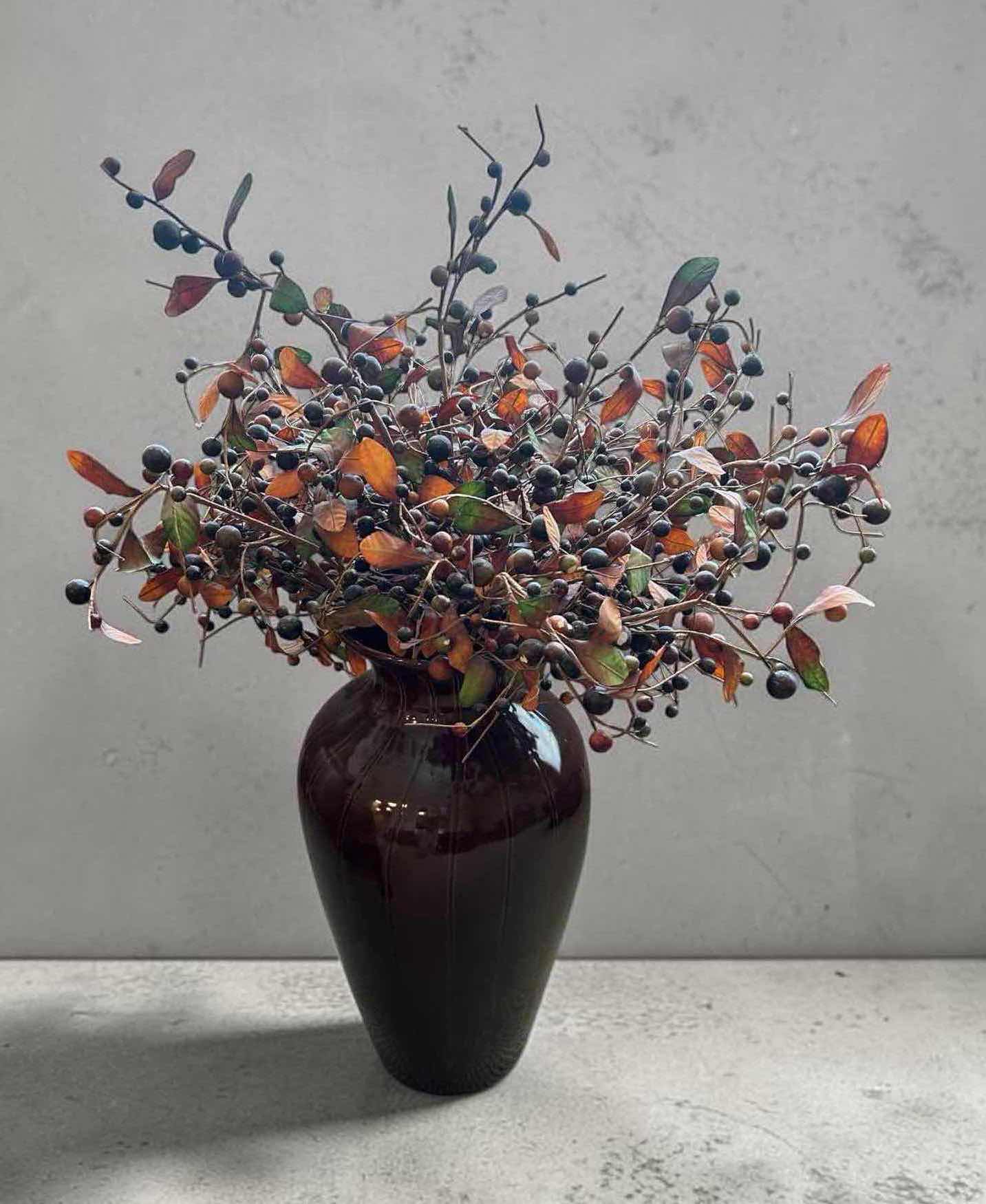 Photo 1 of FAUX BLUE BERRY STEM W ORANGE FOLIAGE IN RED CERAMIC VASE H 3
