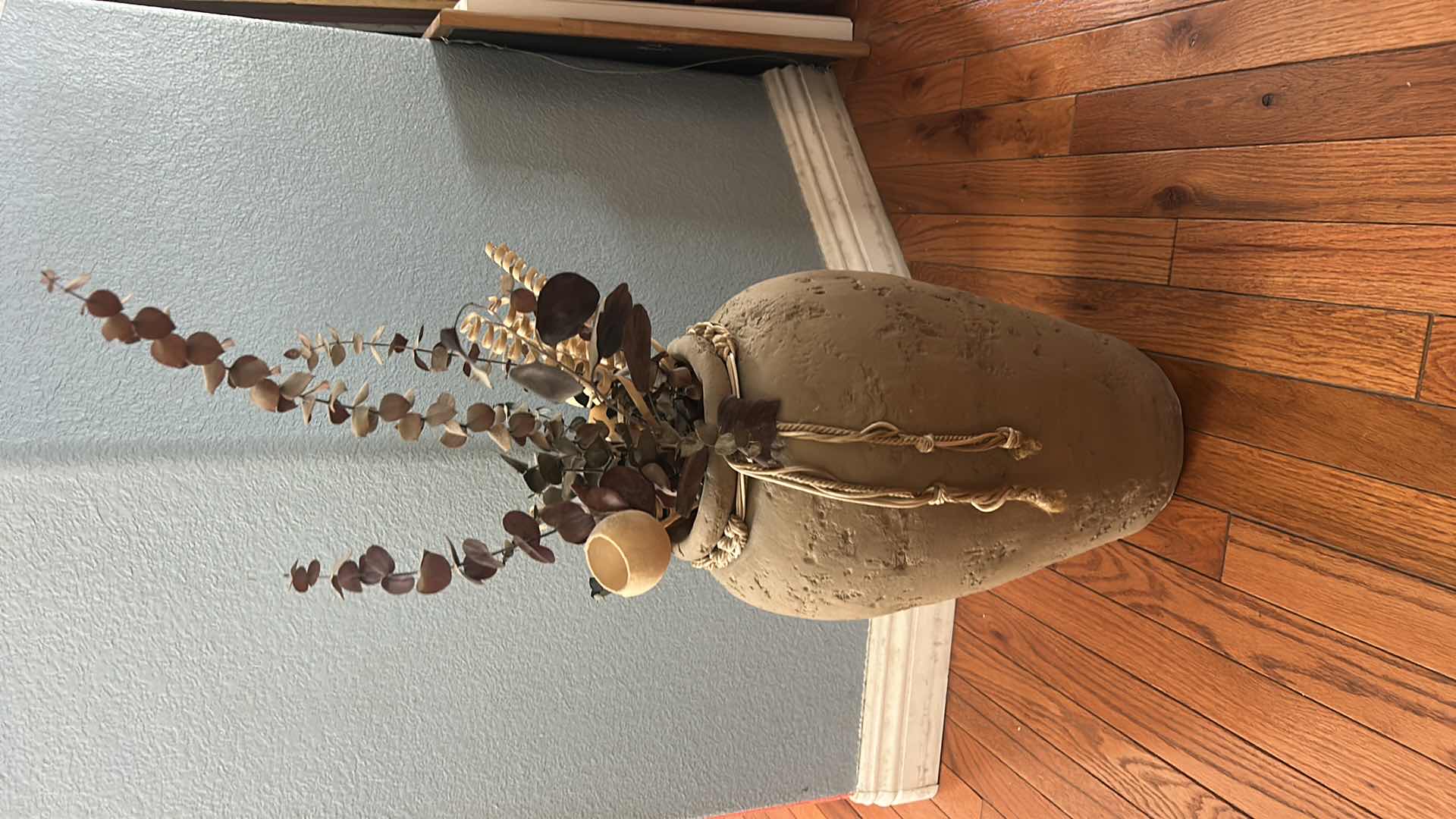 Photo 1 of TERRA-COTTA VASE FEATURING A RUSTIC URN SHAPE WITH A DECORATIVE BRAIDED ROPE, ACCENT AND FAUX FLOWERS H18”