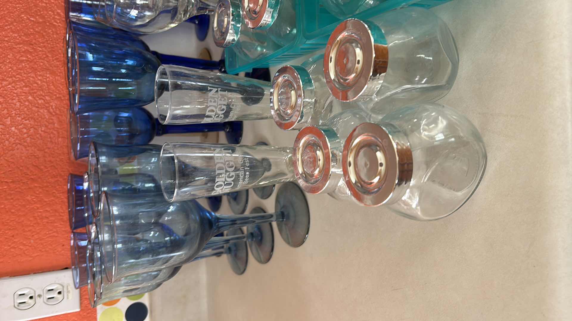 Photo 1 of COLLECTION FEATURING SEVERAL TYPES OF DRINKWARE, INCLUDING VINTAGE CRISTAR SKY BLUE RIOGA WINE, GLASSES AND STEMLESS, GOLDEN NUGGET BRANDED TUMBLERS ARE