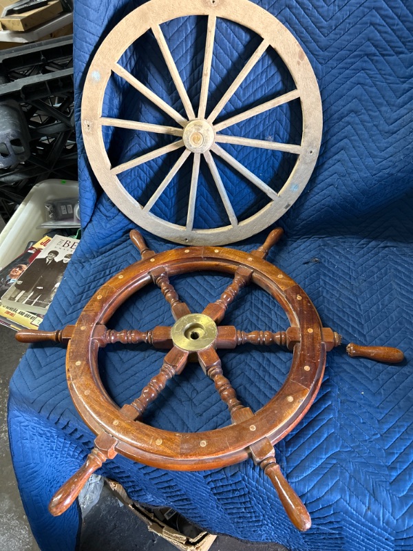 Photo 1 of Wood and brass ships wheel has broken handle that is included also includes wall hanging of wagon wheel 