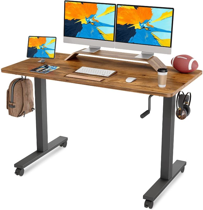 Photo 1 of FAMISKY Crank Adjustable Height Standing Desk, 55 x 24 Inches Manual Stand up Desk, Sit Stand Workstation for Home Office with Handle and Splice Board, Black Frame/Walnut Top
