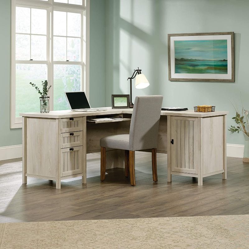 Photo 1 of **BOX A AND BOX B INCLUDED.** SOME WOODEN PANELS HAVE DAMAGE**
Sauder Costa L-Shaped Desk, Chalked Chestnut finish
