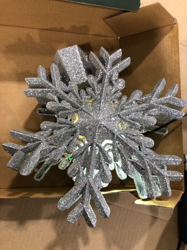 Photo 2 of Christmas Tree Topper Lighted with Built-in Led Rotating Snowflake Projector Lights, 9.6” Hollowed Tree Topper with Silver Spangles Plug In for Indoor Home Xmas New Year Party Holiday Night Tree Decor
