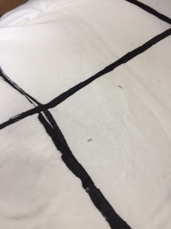 Photo 1 of 66X86INCH WHITE AND BLACK PATTERN BLANKET. DIRT STAINS AND HAIR FOUND ON ITEM. 