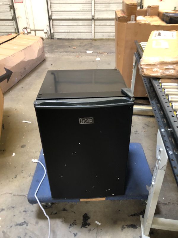 Photo 2 of BLACK+DECKER BCRK25B Compact Refrigerator Energy Star Single Door Mini Fridge with Freezer, 2.5 Cubic Feet, Black. no Bo Packaging, Item is new, item is damaged from shipping and handling, scratchs an scuffs on item, Dent on top corner. Item turns on did 