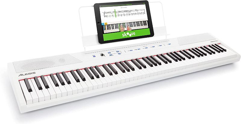 Photo 1 of Alesis Recital – 88 Key Digital Piano Keyboard with Semi Weighted Keys, 5 Voices, Piano Lessons, M-Audio Sustain Pedal and HDH40 Piano Headphones Recital White Piano + Sustain Pedal + Headphones