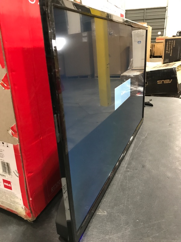 Photo 3 of RCA 32" Class HD (720P) LED TV (RLDED3258A). OPEN BOX. PRIOR USE AS DISPLAY. POWERS ON. FUNCTIONING. DAMAGE AT TOP FRONT EDGE. INCLUDES REMOTE & STAND. 
