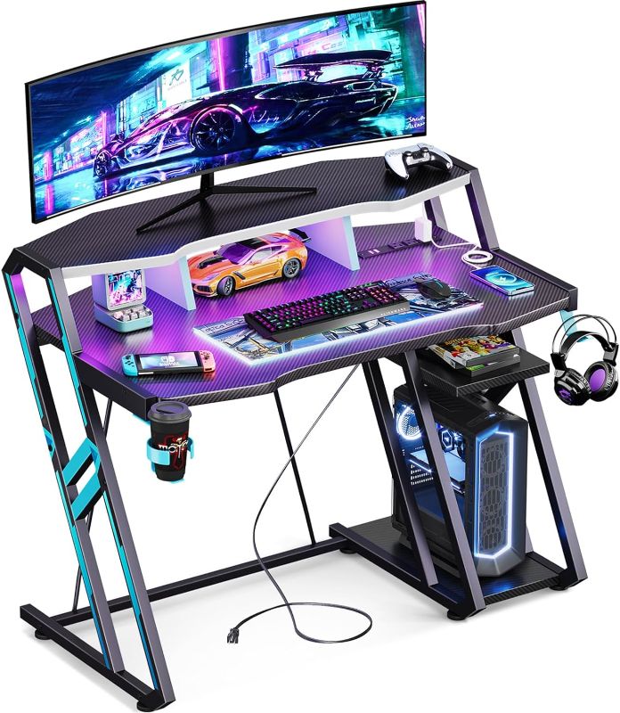 Photo 1 of MOTPK Gaming Desk with Power Outlet & LED Lights, Gaming Computer Desk 39inch with PC Storage Shelf, Gaming Table with Carbon Fiber Texture, Gamer Desk, Gift for Boys Men, Black