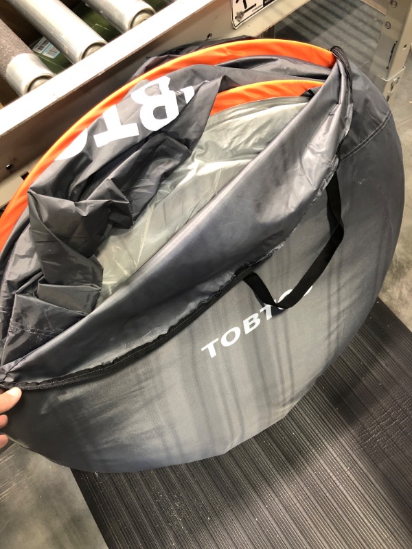 Photo 5 of TOBTOS Camping Instant Tent, Person Pop Up Tent, Water Resistant Dome Tent, Easy Setup for Camping Hiking and Outdoor, Portable Tent with Carry Bag, for 3 Seasons… Black & Orange 
\UNSURE OF SIZE, HAS SAND AND LOOSE GRAVEL INSIDE, BUT TENT SEEMS INTACT.