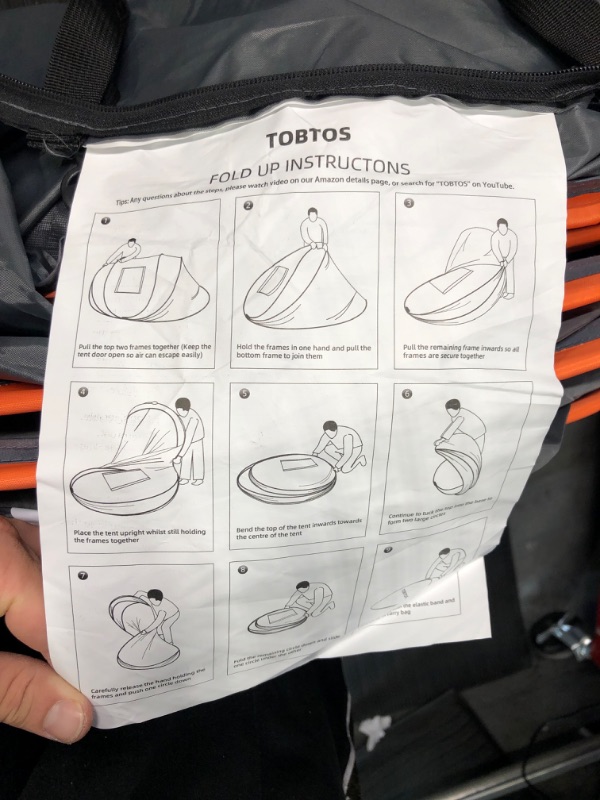 Photo 3 of TOBTOS Camping Instant Tent, Person Pop Up Tent, Water Resistant Dome Tent, Easy Setup for Camping Hiking and Outdoor, Portable Tent with Carry Bag, for 3 Seasons… Black & Orange 
\UNSURE OF SIZE, HAS SAND AND LOOSE GRAVEL INSIDE, BUT TENT SEEMS INTACT.