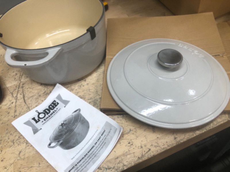 Photo 1 of **HANDLE IS CHIPPED***
Lodge 6 Quart Enameled Cast Iron Dutch Oven with Lid – Dual Handles – Oven Safe up to 500° F or on Stovetop - Use to Marinate, Cook, Bake, Refrigerate and Serve – Oyster White

