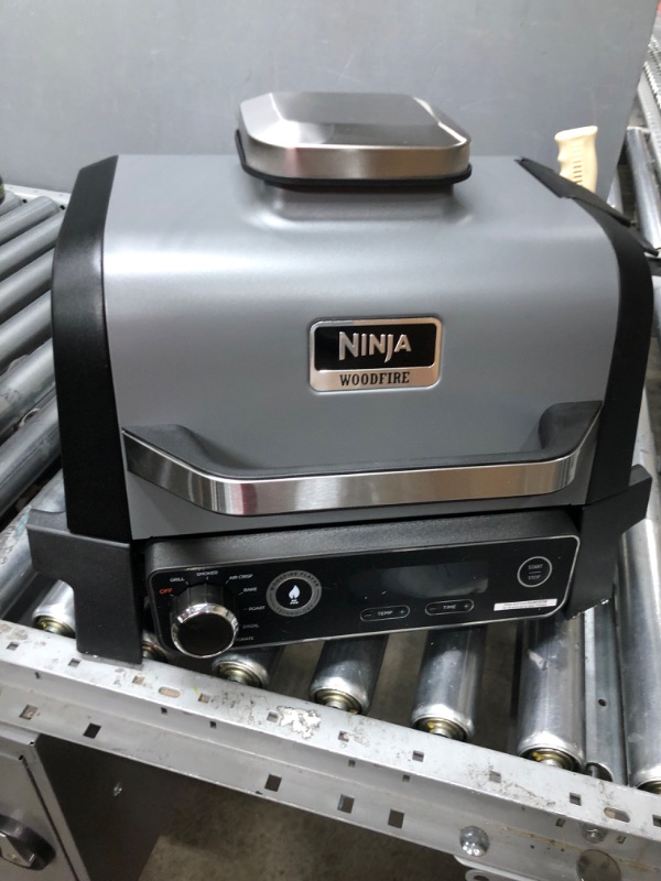 Photo 1 of Ninja OG701 Woodfire Outdoor Grill & Smoker, 7-in-1 Master Grill, BBQ Smoker, & Air Fryer plus Bake, Roast, Dehydrate, & Broil, uses Ninja Woodfire Pellets, Weather-Resistant, Portable, Electric, Grey