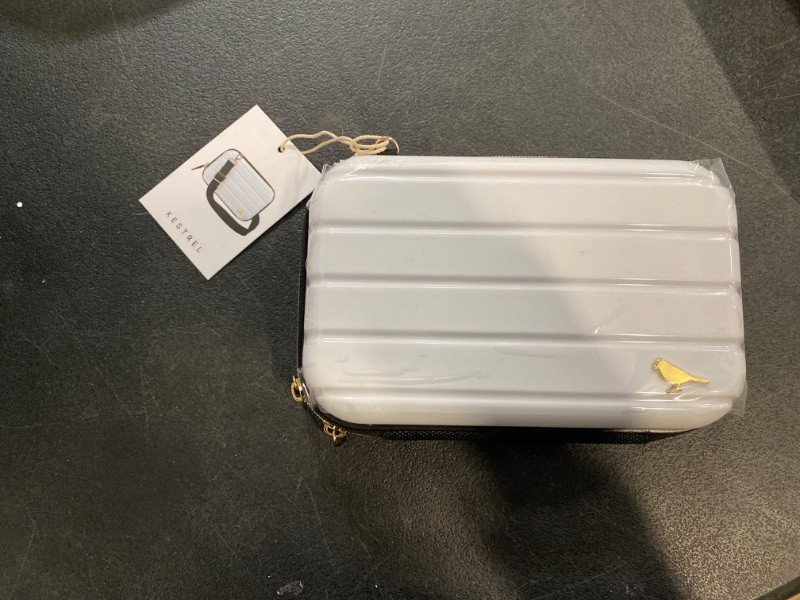 Photo 2 of    White Mini Molded Hard Case - White Mini Molded Hard Case by Kestrel with black trim and adjustable crossbody strap, gold-tone hardware. Features Gold-tone hardware with black trim Rubber branded zipper pullers Spacious main compartment for essentials 