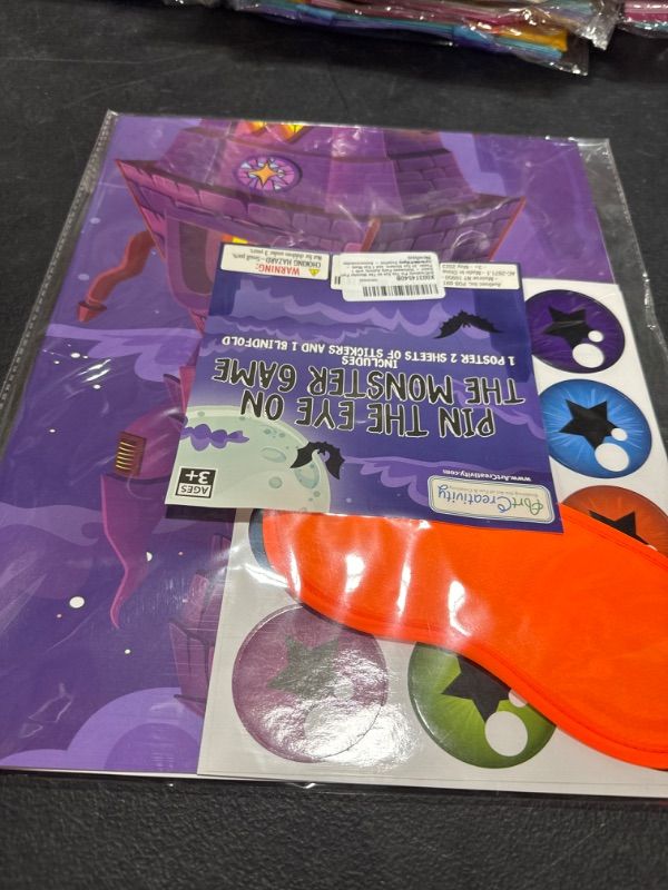 Photo 1 of ArtCreativity Pin The Eye on The Monster Party Game - Halloween Party Activity with 1 Sign, 24 Eye Stickers, and 1 Eye Mask - Halloween Party Supplies - Accommodates Up to 24 Players
