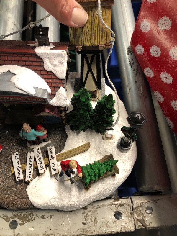 Photo 2 of **DAMAGED, SOME PIECES BROKEN AND CAN BE REGLUED***
MOMENTS IN TIME Christmas Village Building, 6.7”H Polyresin Christmas Tree Lot with LED Lightup & Music - Battery Operated (not Included)