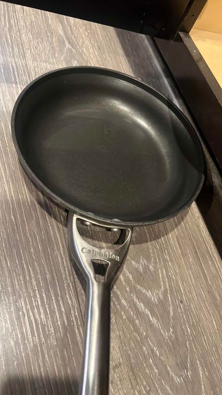 Photo 1 of CONTENTS OF CABINET PANS, SKILLETS, LARGE SERVING PLATES, AND A  CALPHALON PAN