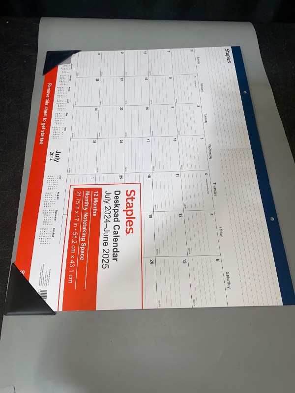 Photo 1 of Staples Deskpad Calendar for July 2024-June 2025. It has a monthly view with a notetaking space, and the dimensions are 21.75 in x 17 in (55.2 cm x 43.1 cm)