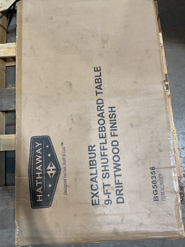 Photo 1 of ***USED, MAJOR DAMAGE TO ONE CORNER***Hathaway Excalibur 9-Ft Shuffleboard Table for Great for Family Recreation Game Rooms, Designed with a Rustic Driftwood Finish with Built-In Leg Levelers, Includes 8 Pucks, Table Brush and Wax