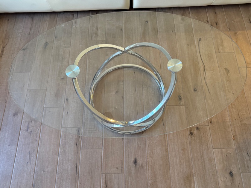 Photo 1 of CONTEMPORARY OVAL CLEAR GLASS COFFEE TABLE W CHROME-TONE METAL RINGS BASE 49" x 28"  H19"