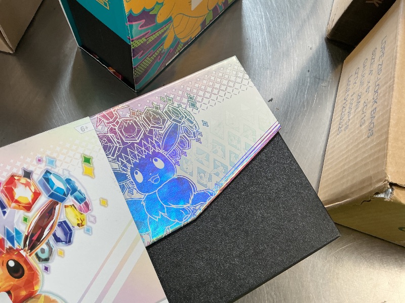Photo 1 of Pokémon: Scarlet & Purple Elite Trainer Set - Prismatic Evolutions of the Pokémon TCG (1 Fully Illustrated Promo Card, 9 Booster Packs & Premium Game Accessories)