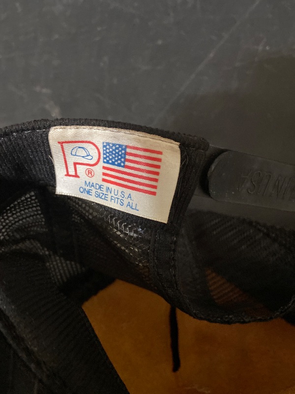 Photo 1 of vintage black trucker hat features a white embroidered "INSTRUCTOR" patch with an aviation-inspired logo.