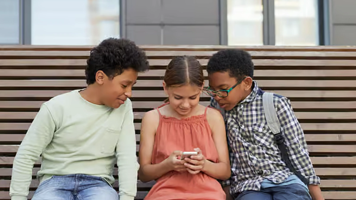 Children looking at a smartphone representing social media age verification rules