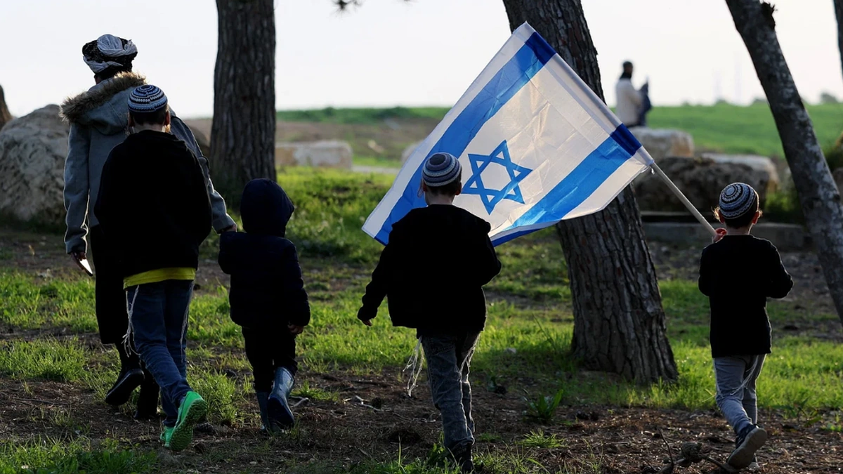 Children carrying an Israeli flag near a settlement area