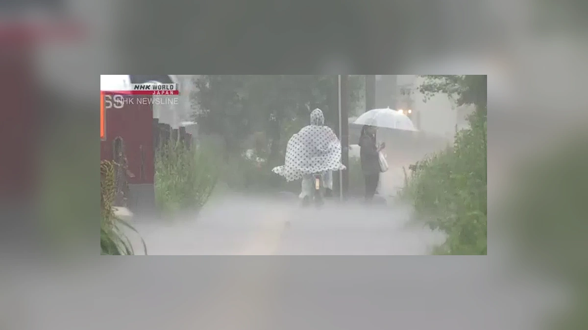 People walking through heavy rain in Japan under emergency weather warning