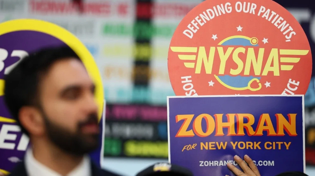 Supporter holding a Zohran Mamdani campaign sign in New York