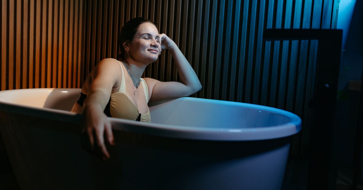 Serene woman enjoying a relaxing bath in a modern interior with ambient lighting.