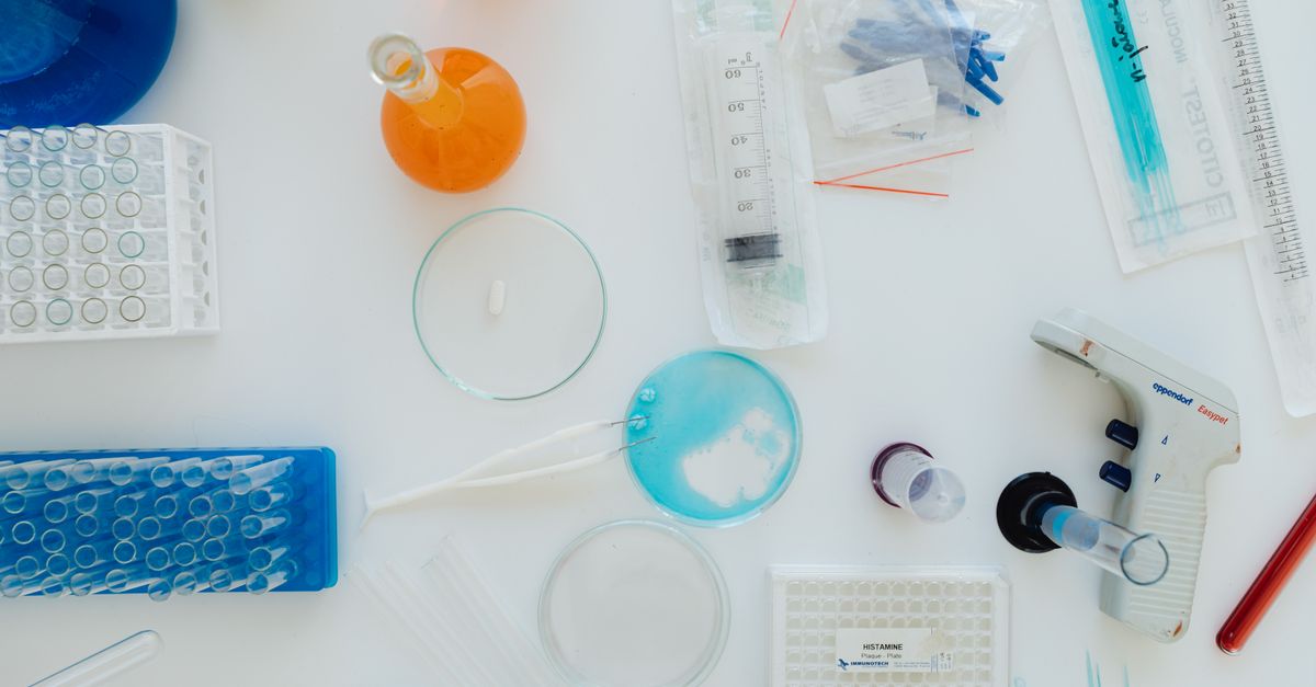 Top view of various lab tools and containers on a white surface. Perfect for science-related content.