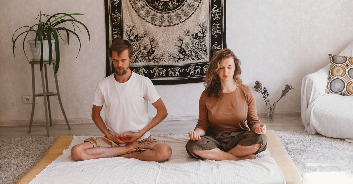 A serene atmosphere with two adults meditating indoors on a mat, embracing mindfulness.