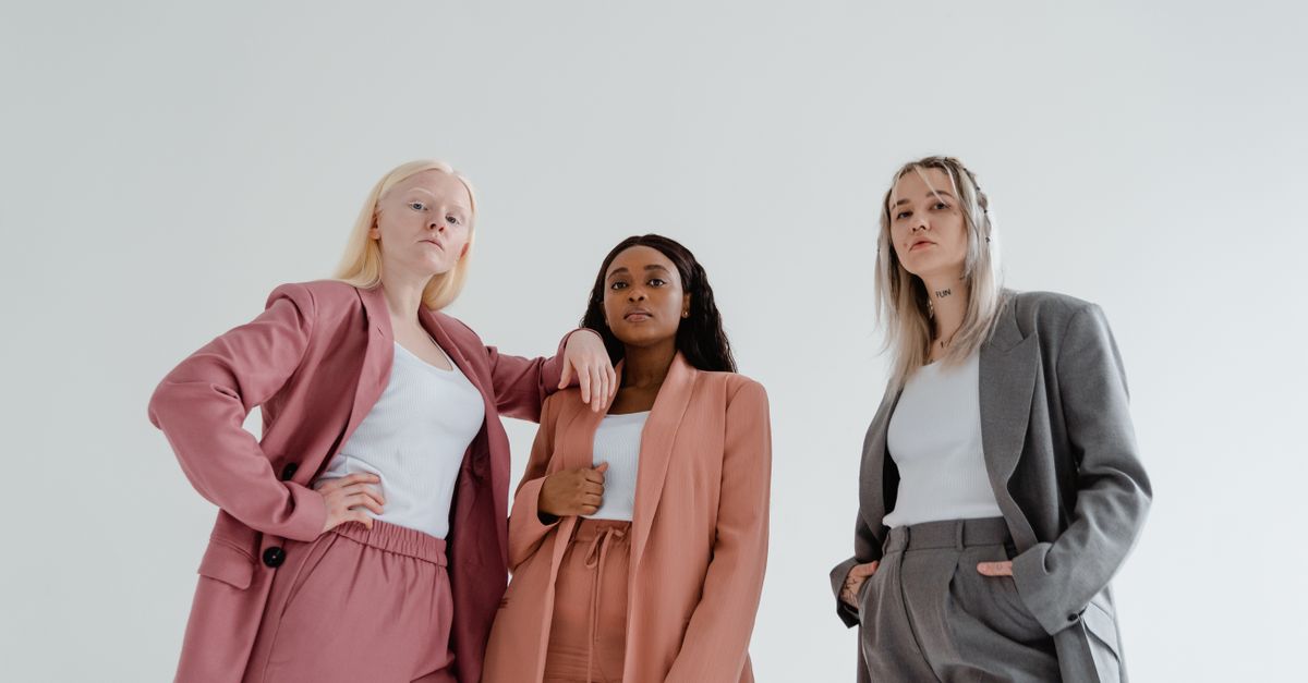 Three diverse women posing confidently in fashion-forward blazers against a white background.
