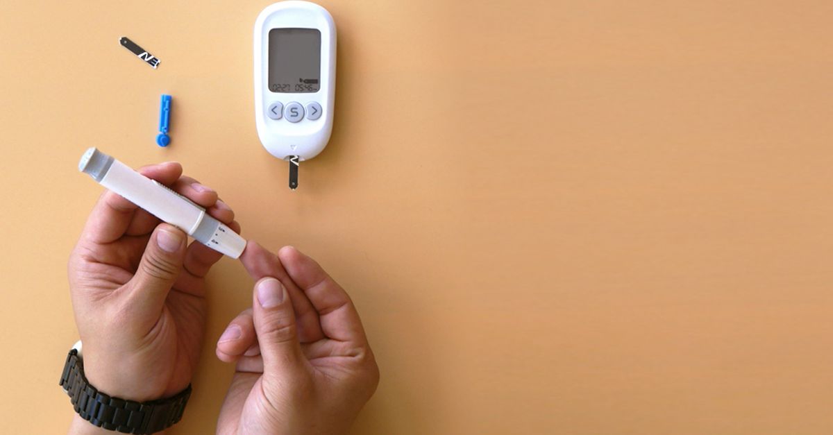 Hands testing blood sugar with a glucose meter on a beige background.