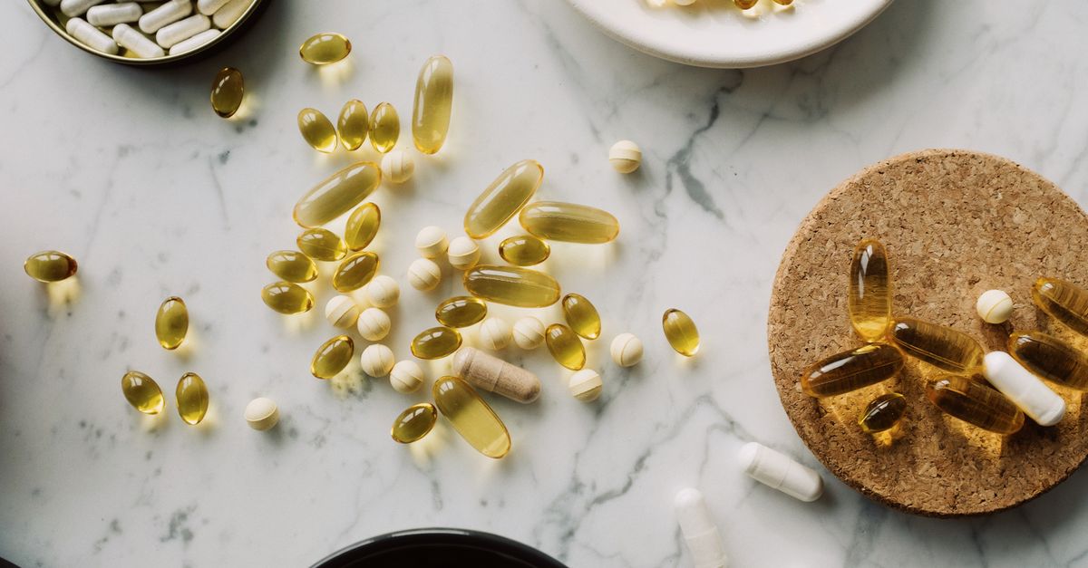 Health supplements and vitamins in gelatin capsules arranged in various container on marble surface