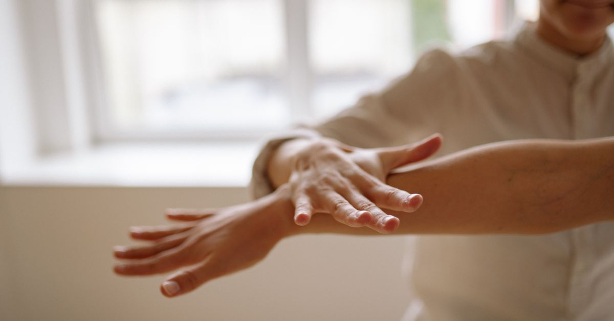 A close-up view of a person using a relaxation technique with hands in motion, in a bright, airy space.