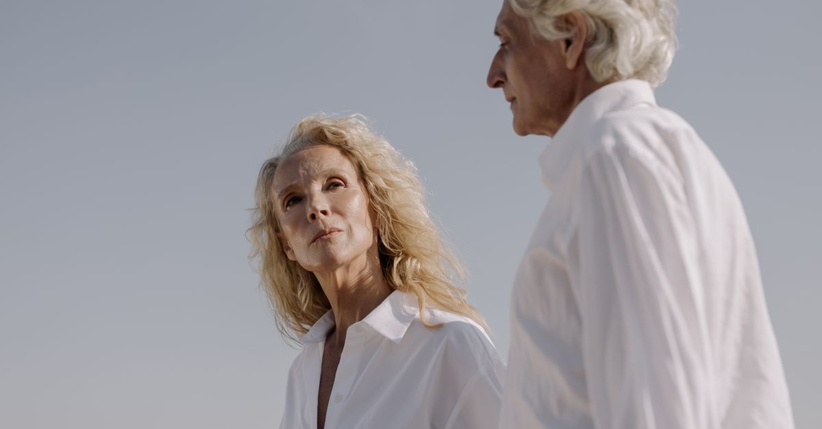 Elderly couple in white shirts gazing thoughtfully, capturing warmth and wisdom.