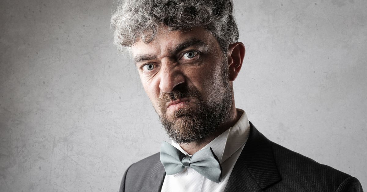 Close-up shot of a serious bearded man in formal wear. Studio photography.