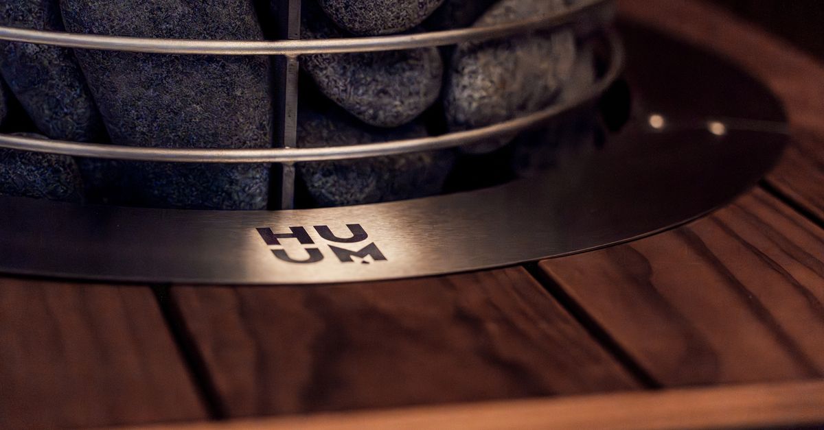 Close-up of a modern sauna heater with stones on a wooden platform, showcasing Nordic design.