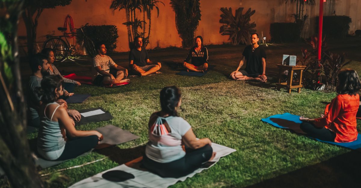 Group practicing yoga outdoors at night for relaxation and wellness.