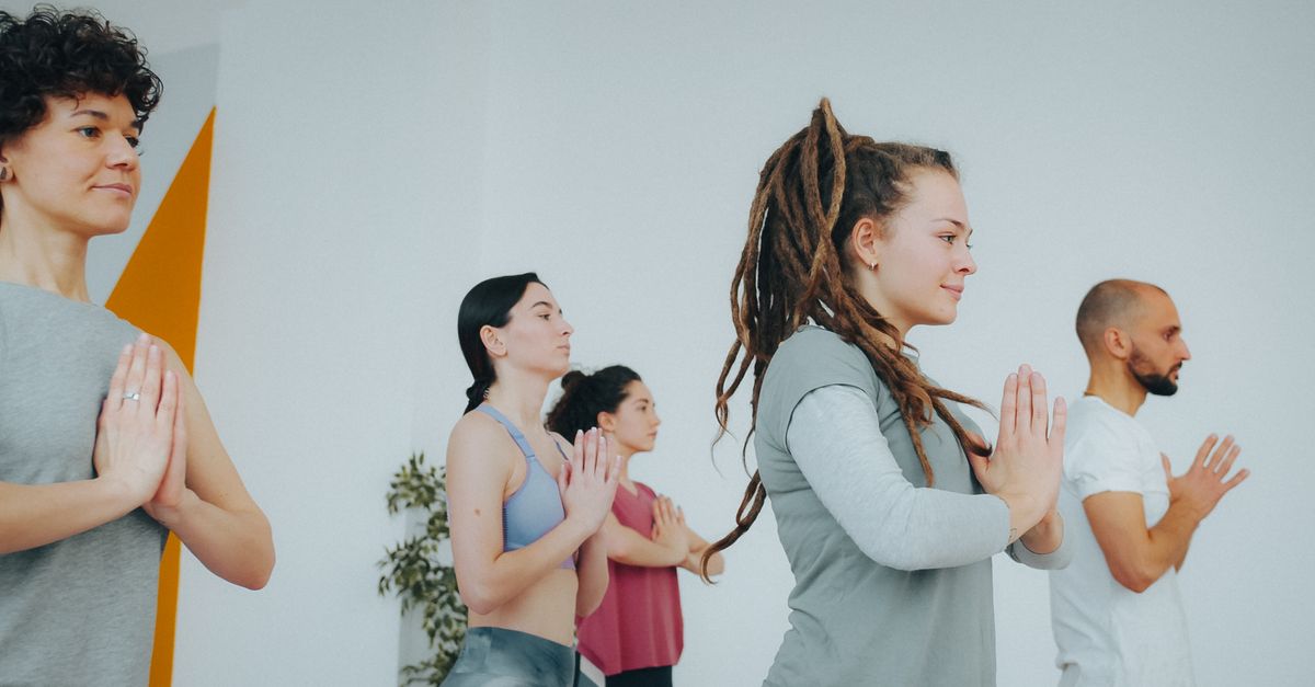 Diverse group of adults practicing yoga indoors, maintaining focus and calmness.