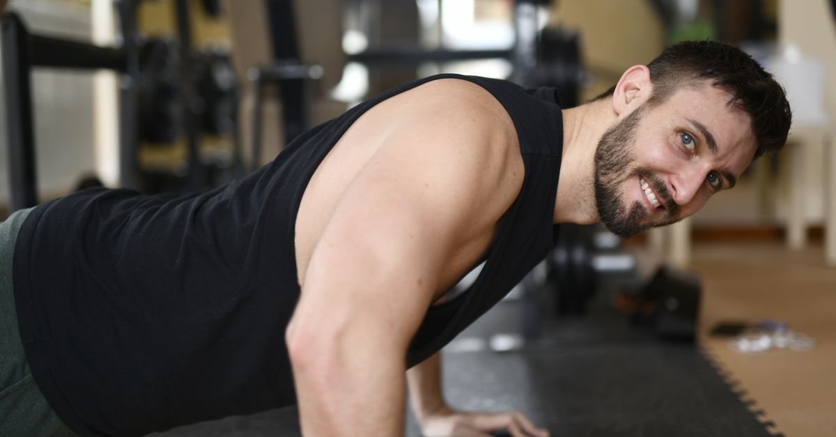 Adult male performing push-ups in a gym. Strong fitness routine showcasing effort and determination.