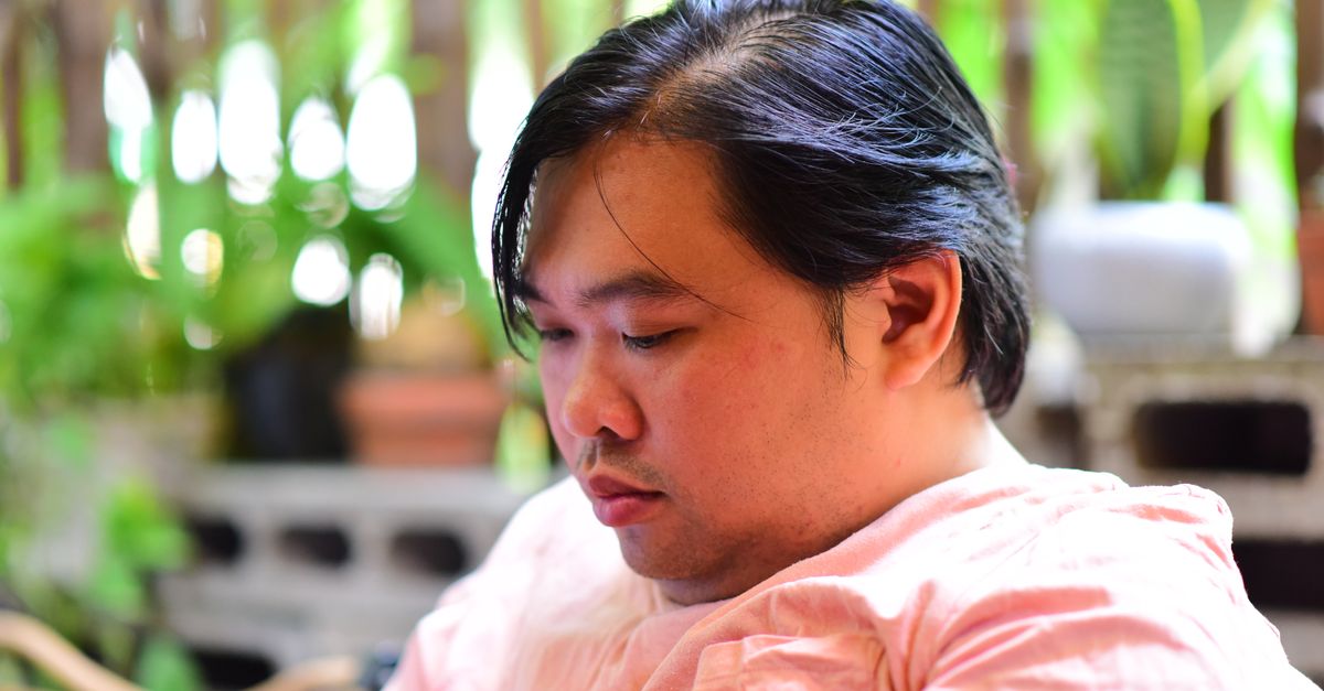 A thoughtful man enjoying a quiet moment in a lush garden, surrounded by green plants.