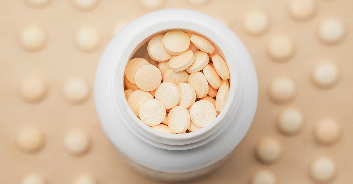 High-angle shot of a white bottle filled with round tablets on a textured background.
